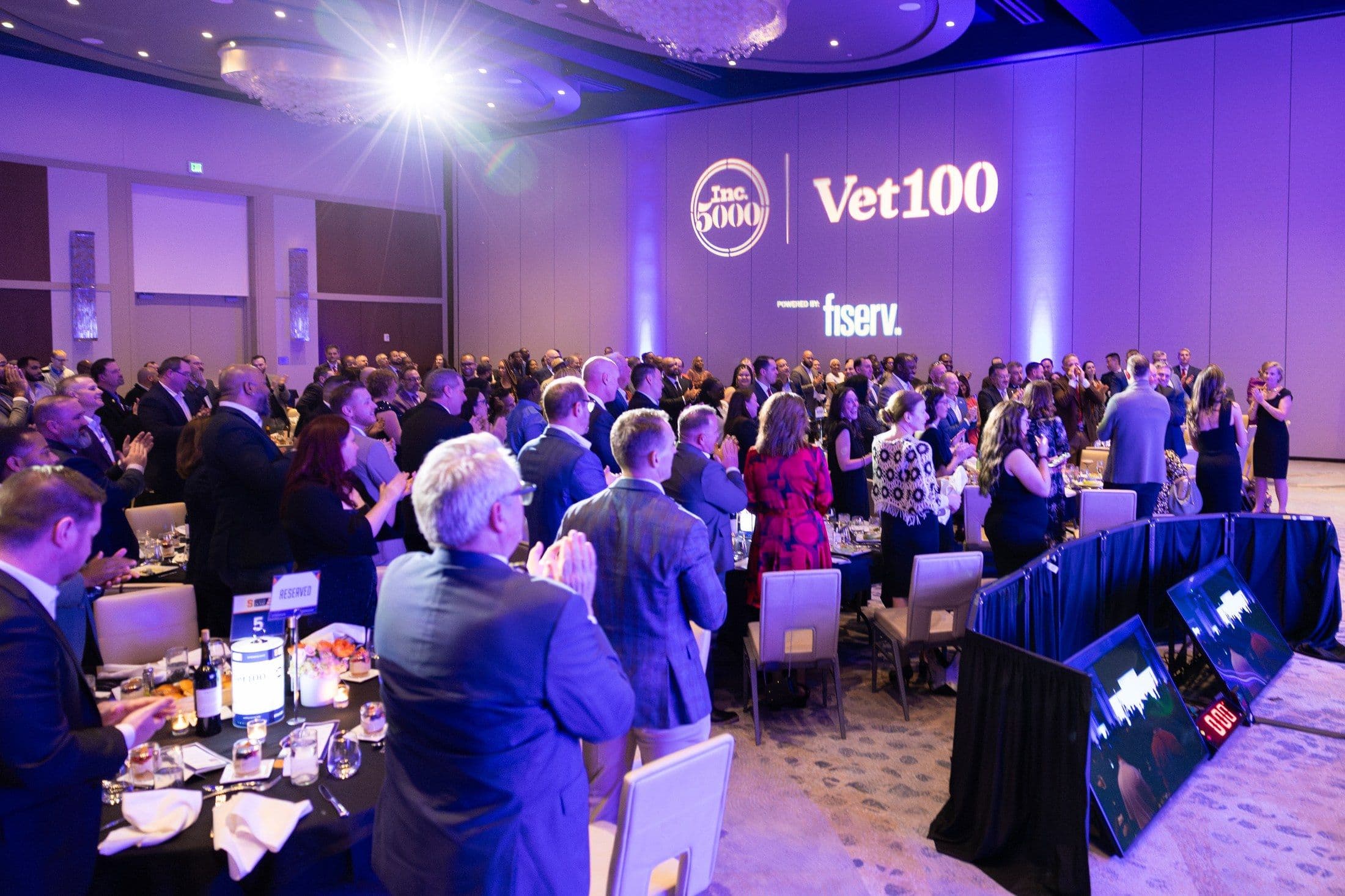 The Vet100 awards room in Dallas, with Inc. 5000 and Fiserv visible on stage.